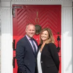 two people standing in front of the nassau inn red front door
