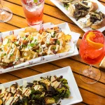 nachos, brussels sprouts and drinks on patio table