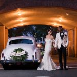 a wedding couple outside a hotel next to a vintage car in a driveway with just married sign on back of car
