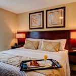 close up of a hotel room double bed with a serving tray on the corner