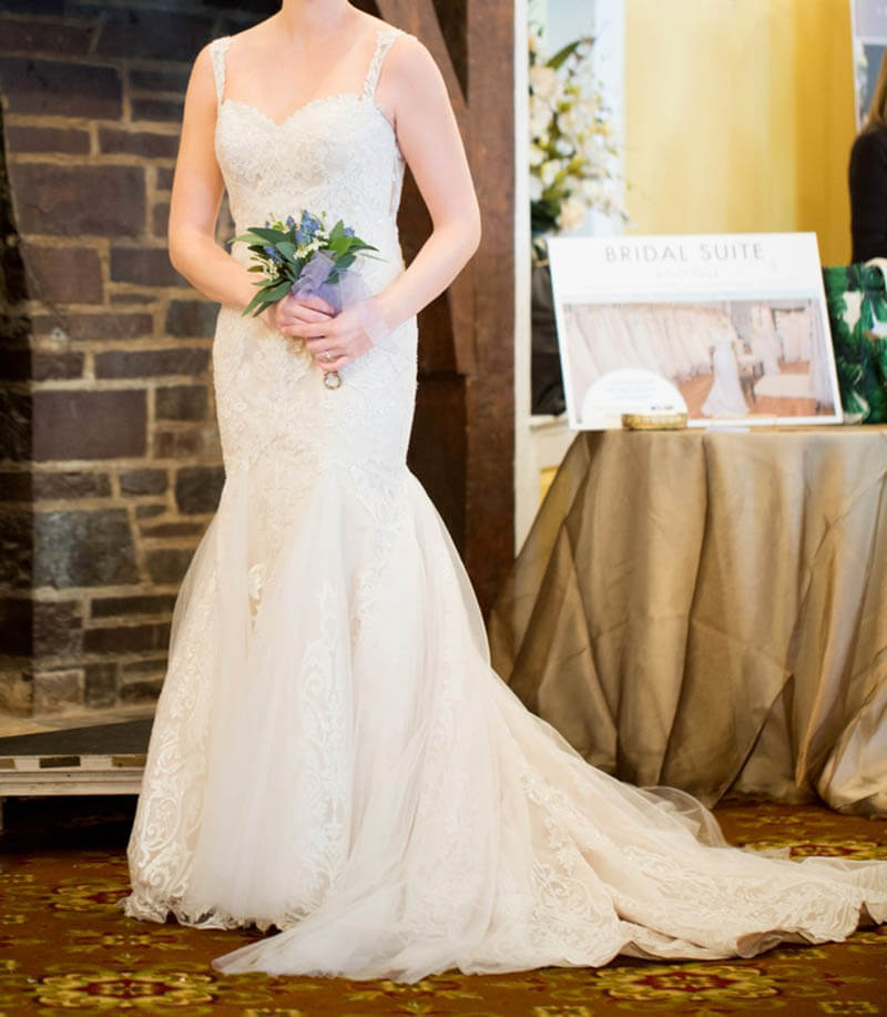 model wearing lace bridal gown, holding a small bouquet