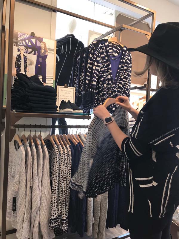 woman by clothing rack looking at items