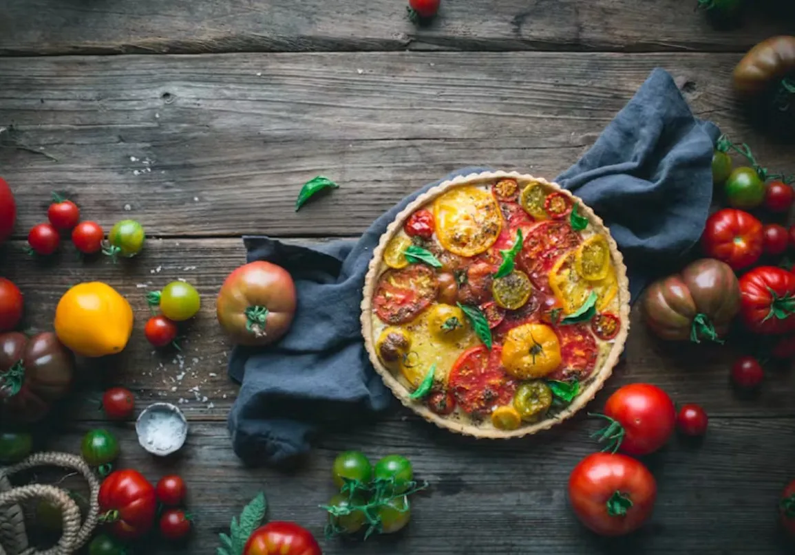 tomato galette with tomatoes scattered on table around it