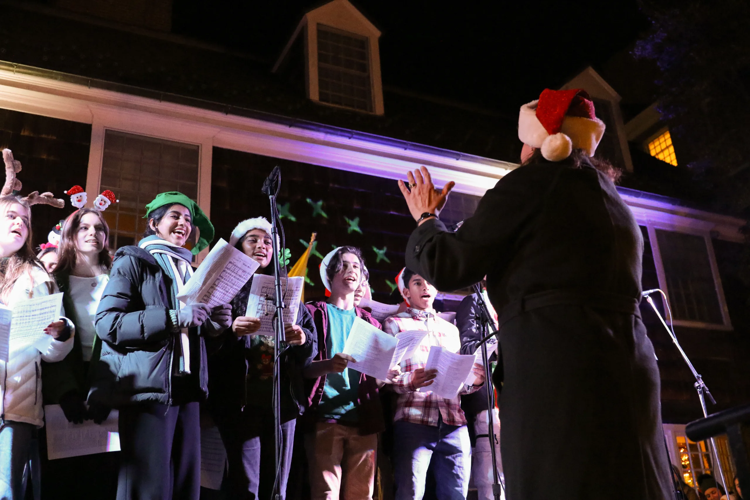 a choir preforming with a conductor wearing a Santa hat