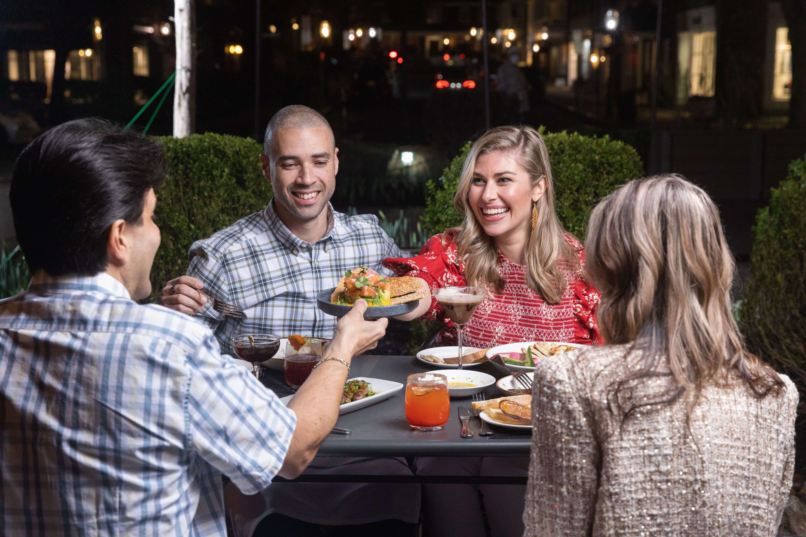 couples passing platters and enjoying an evening outside dining