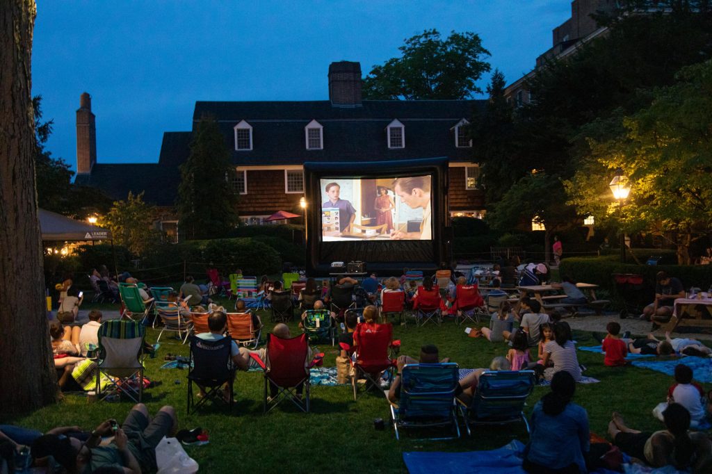 inflatable movie screen with audience on sitting in chairs on the grass in front of the Nassau Inn hotel