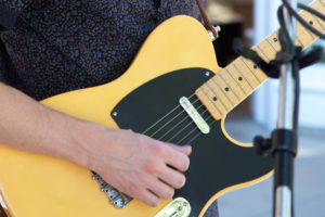 close up of a hand strumming an electric guitar
