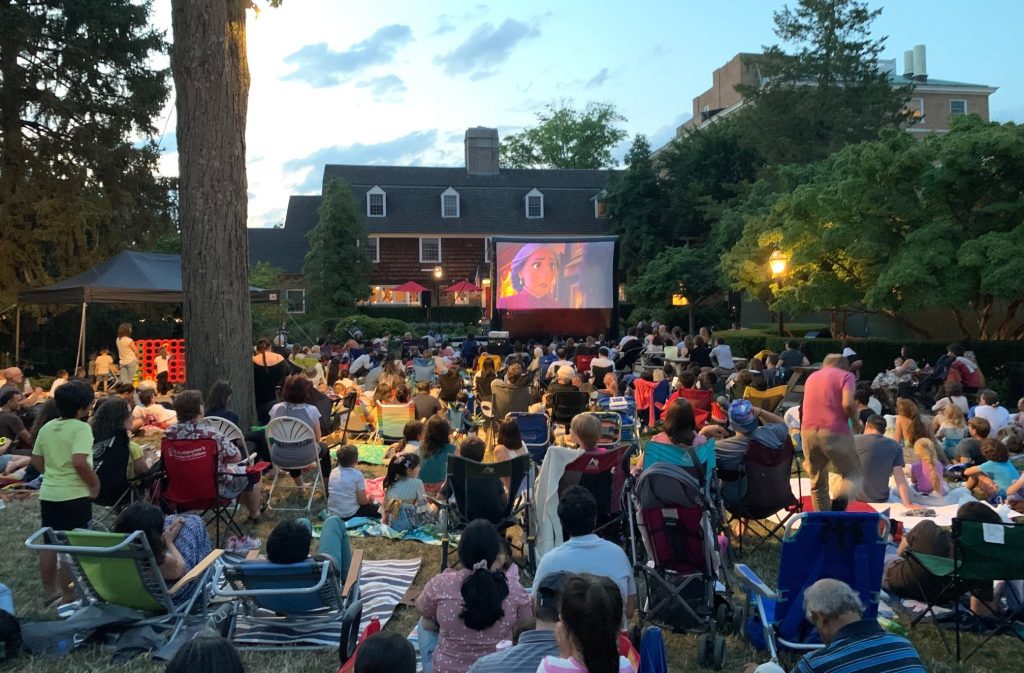 inflatable movie screen with audience on sitting in chairs on the grass in front of the Nassau Inn hotel