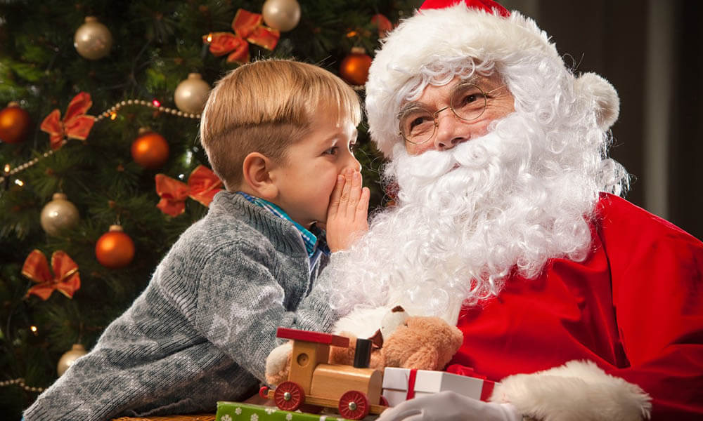 child whispering into santas ear