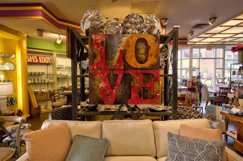 inside Homestead Princeton, rustic LOVE sign overhead a beige couch 