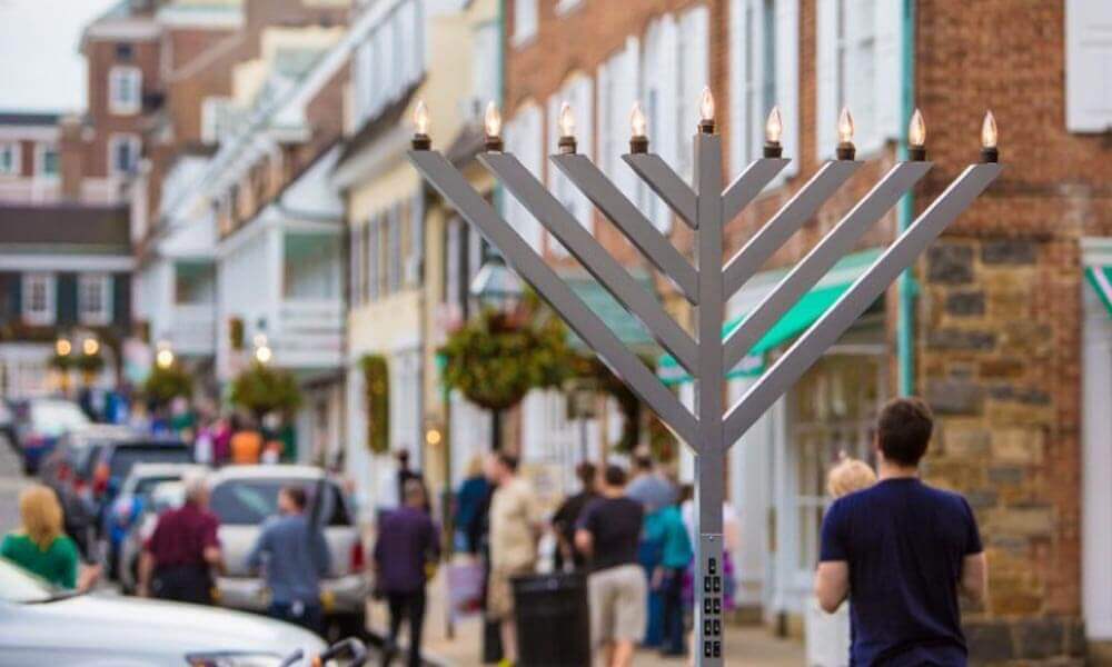Menorah lit in the square as patrons pass by